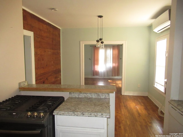 kitchen with black gas stove, dark hardwood / wood-style flooring, plenty of natural light, and a wall mounted air conditioner