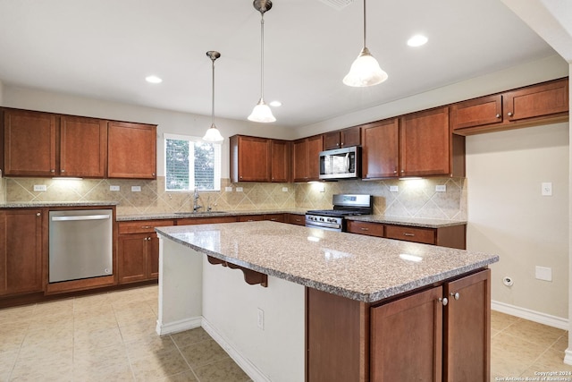 kitchen featuring sink, light stone counters, decorative light fixtures, a kitchen island, and appliances with stainless steel finishes