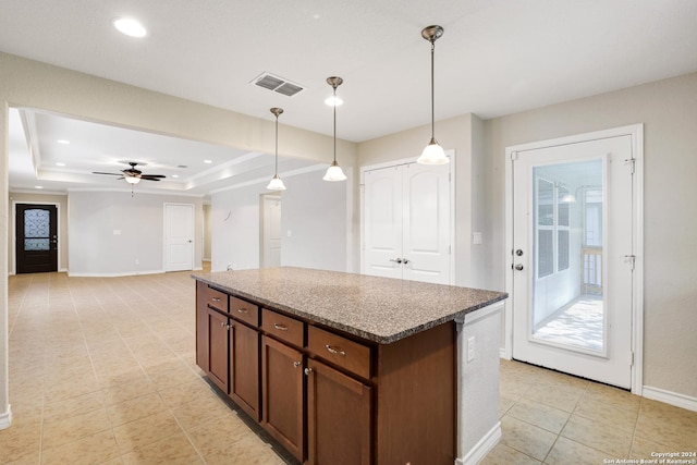 kitchen with ceiling fan, a center island, decorative light fixtures, a tray ceiling, and light tile patterned floors