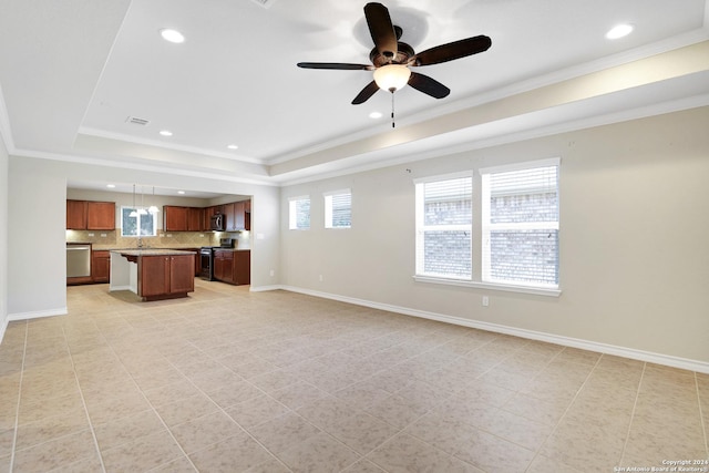 unfurnished living room with ceiling fan, sink, crown molding, a tray ceiling, and light tile patterned floors