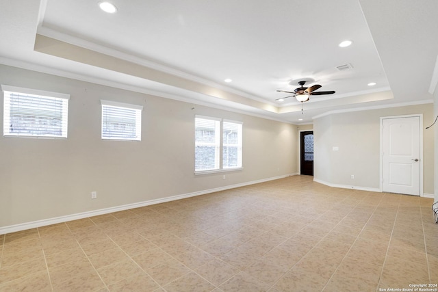 tiled empty room with a raised ceiling, ceiling fan, and crown molding