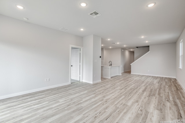 unfurnished living room featuring light hardwood / wood-style floors and sink