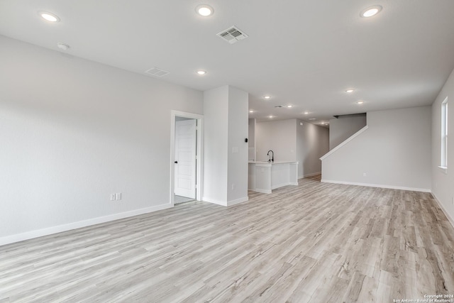 unfurnished living room with sink and light hardwood / wood-style flooring