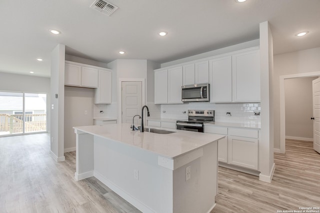 kitchen featuring an island with sink, appliances with stainless steel finishes, sink, and white cabinets