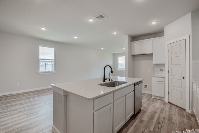 kitchen with backsplash, sink, stainless steel dishwasher, an island with sink, and white cabinetry