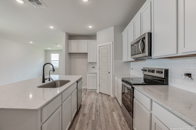 kitchen with a center island with sink, sink, white cabinetry, and stainless steel appliances