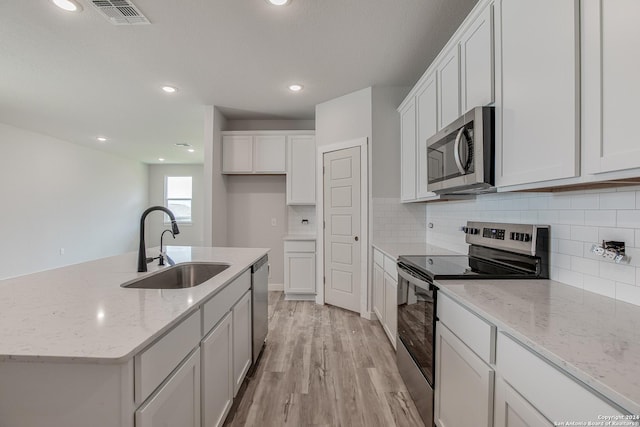 kitchen featuring stainless steel appliances, white cabinetry, sink, and an island with sink