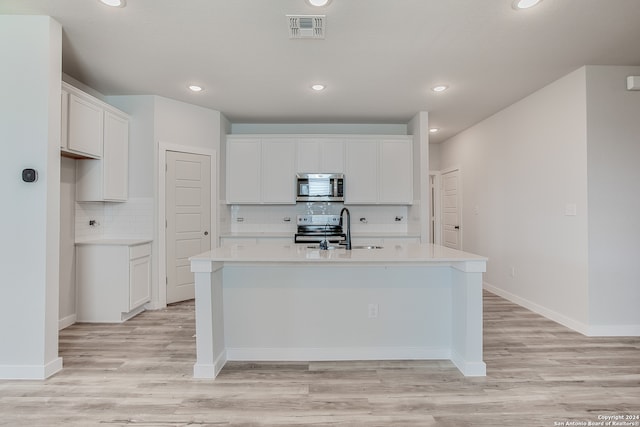 kitchen with sink, white cabinetry, stainless steel appliances, and a kitchen island with sink