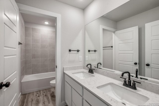 full bathroom featuring hardwood / wood-style flooring, vanity, toilet, and tiled shower / bath