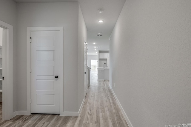 corridor with sink and light hardwood / wood-style floors