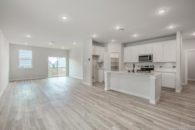 kitchen with light hardwood / wood-style flooring, white cabinetry, stainless steel appliances, and an island with sink