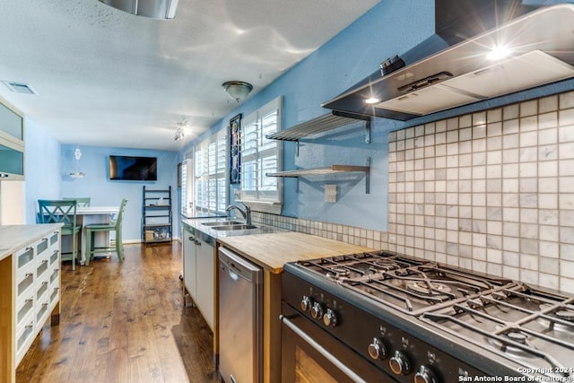 kitchen with dark hardwood / wood-style flooring, backsplash, stainless steel dishwasher, wall chimney exhaust hood, and range with gas cooktop