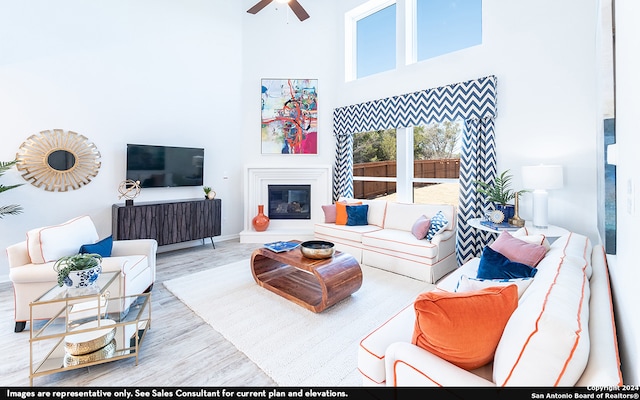 living room with a towering ceiling, hardwood / wood-style flooring, and ceiling fan