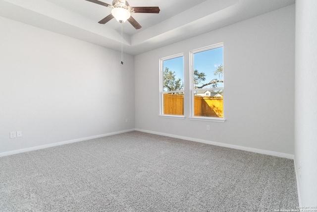 carpeted spare room featuring ceiling fan and a raised ceiling