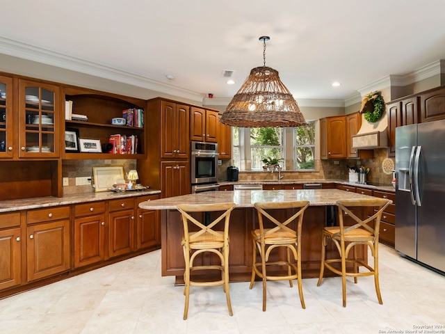 kitchen featuring decorative light fixtures, backsplash, a kitchen island, appliances with stainless steel finishes, and a kitchen breakfast bar