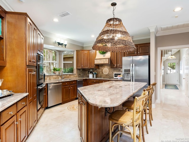 kitchen with appliances with stainless steel finishes, tasteful backsplash, ornamental molding, a wealth of natural light, and a center island