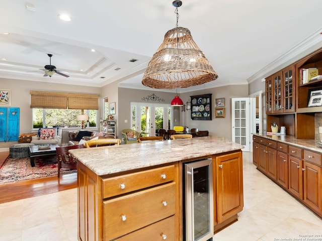 kitchen featuring ornamental molding, beverage cooler, light stone counters, and a center island