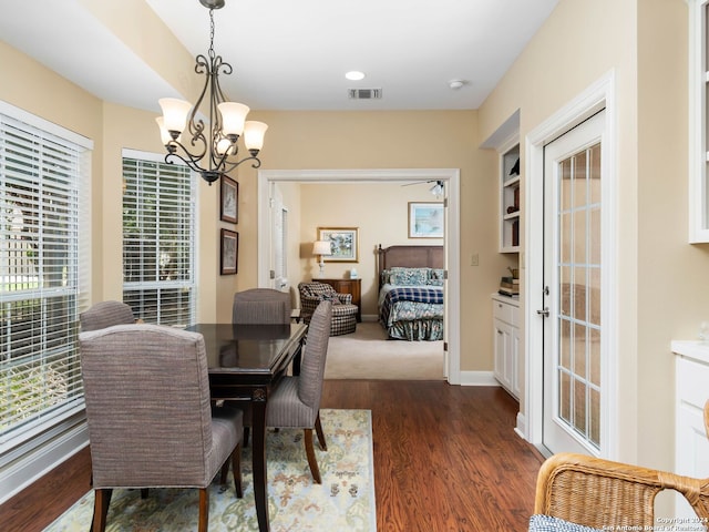 dining area featuring dark wood-type flooring and an inviting chandelier