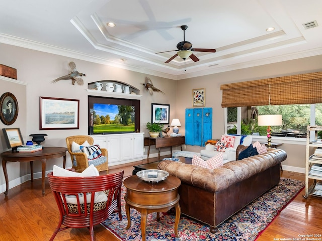 living room featuring a tray ceiling, crown molding, and light wood-type flooring