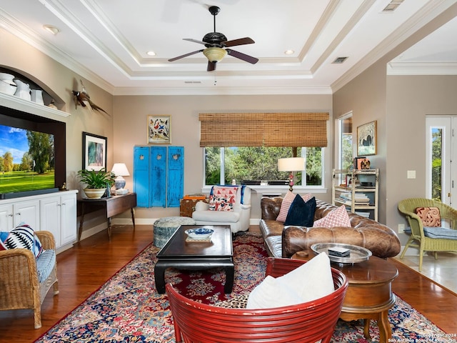 living room with a wealth of natural light, ornamental molding, and a raised ceiling