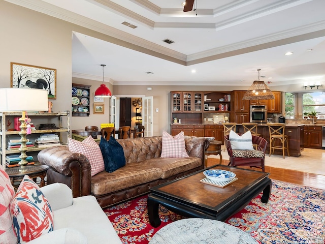 living room with sink, ornamental molding, ceiling fan, a tray ceiling, and light hardwood / wood-style flooring