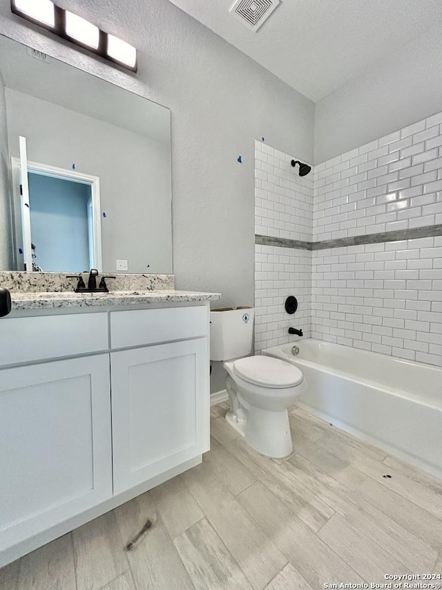 full bathroom with vanity, tiled shower / bath combo, and toilet