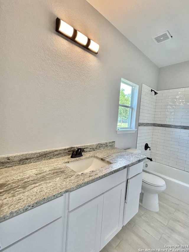 full bathroom with toilet, vanity, and tiled shower / bath