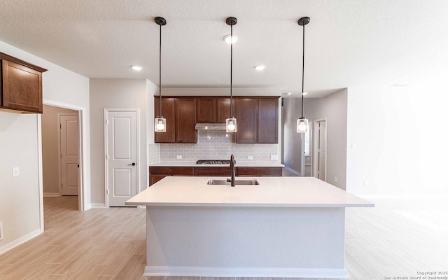 kitchen featuring a kitchen island with sink, sink, and pendant lighting