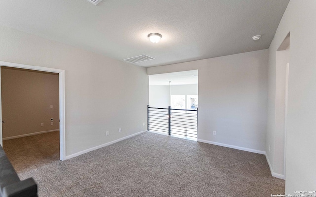 carpeted empty room featuring a textured ceiling