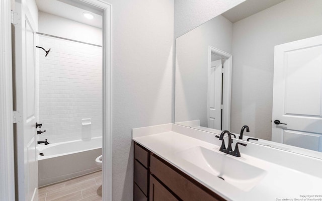 full bathroom featuring tiled shower / bath, vanity, and toilet