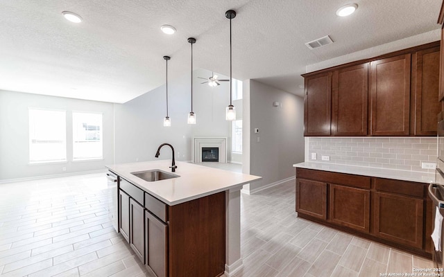 kitchen with plenty of natural light, decorative backsplash, sink, and a center island with sink