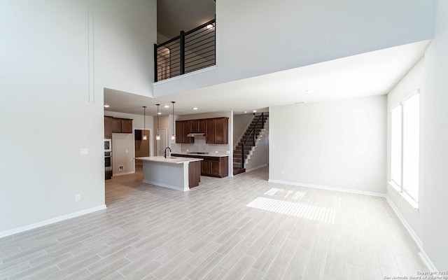 unfurnished living room featuring sink, a healthy amount of sunlight, and light hardwood / wood-style floors