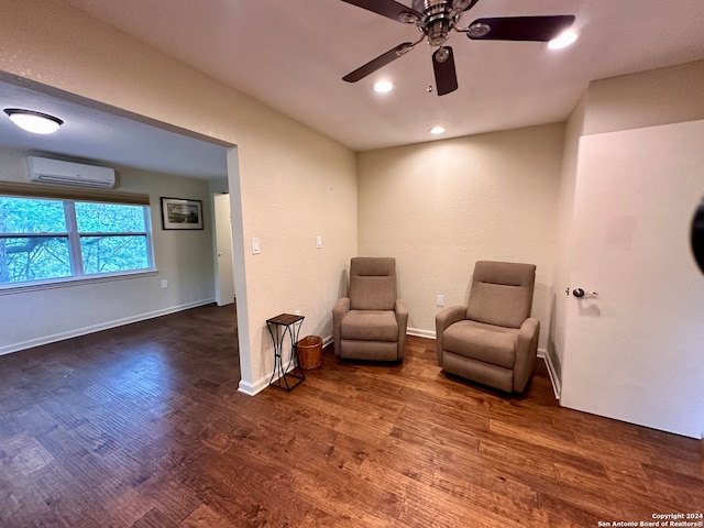 sitting room featuring dark hardwood / wood-style floors, ceiling fan, and an AC wall unit