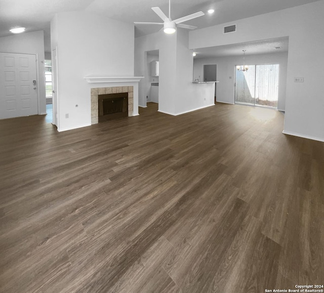 unfurnished living room with ceiling fan with notable chandelier, dark hardwood / wood-style flooring, lofted ceiling, and a fireplace