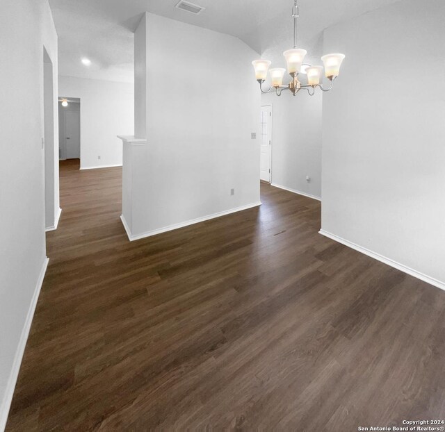 spare room with dark wood-type flooring and a chandelier