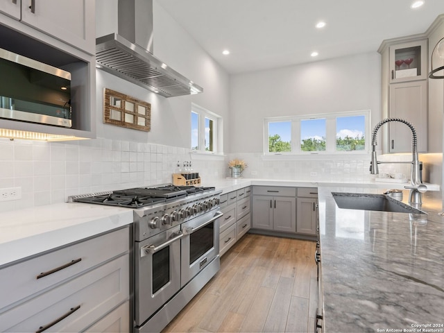 kitchen with appliances with stainless steel finishes, sink, wall chimney exhaust hood, and tasteful backsplash