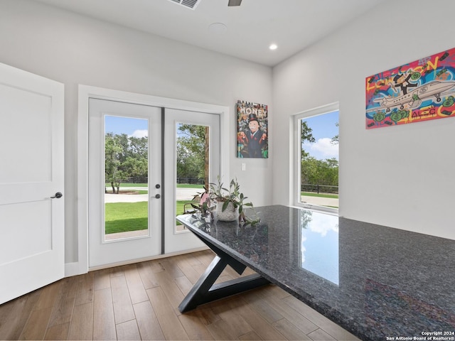 unfurnished dining area featuring french doors, a wealth of natural light, and dark wood-type flooring