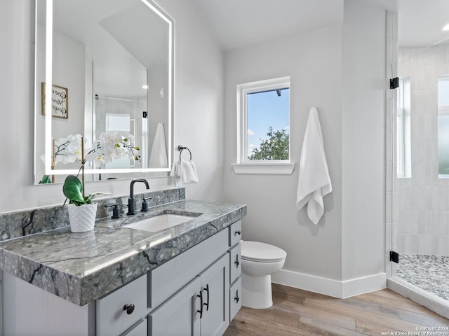 bathroom with tiled shower, large vanity, toilet, and hardwood / wood-style floors