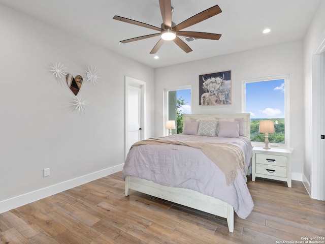 bedroom with ceiling fan, light hardwood / wood-style floors, and multiple windows