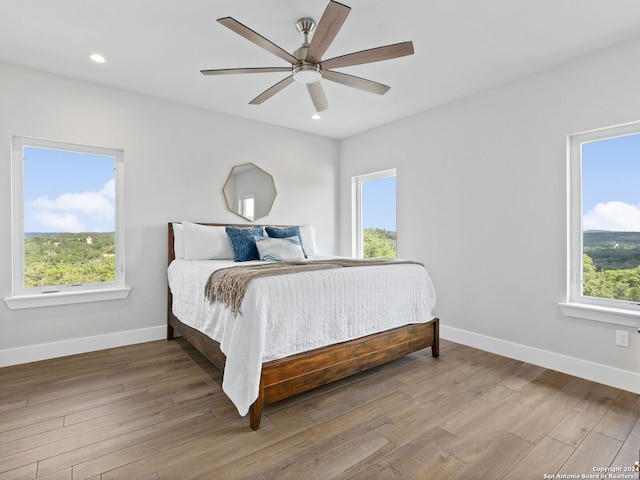 bedroom featuring ceiling fan, hardwood / wood-style flooring, and multiple windows