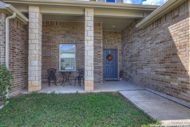 doorway to property with a lawn and a porch