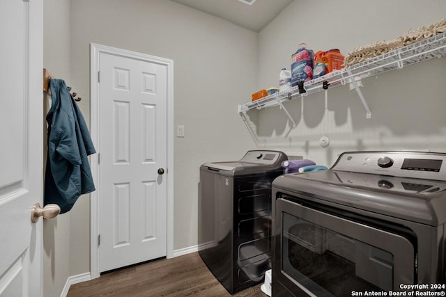 laundry room featuring washing machine and clothes dryer and dark hardwood / wood-style flooring