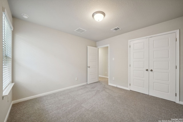 unfurnished bedroom with a closet, carpet floors, and a textured ceiling