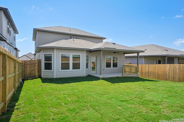 rear view of property featuring a lawn and ceiling fan