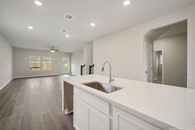 kitchen featuring dark hardwood / wood-style flooring, light stone counters, ceiling fan, sink, and white cabinetry