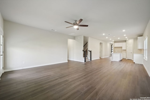 unfurnished living room with ceiling fan and dark wood-type flooring