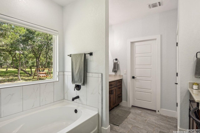 bathroom with vanity, plenty of natural light, and a tub