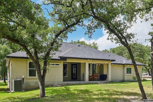 back of property with central AC unit and a yard