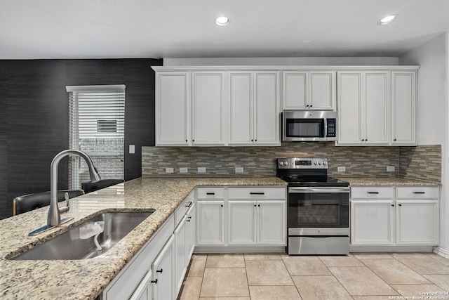 kitchen featuring backsplash, white cabinets, sink, light tile floors, and appliances with stainless steel finishes