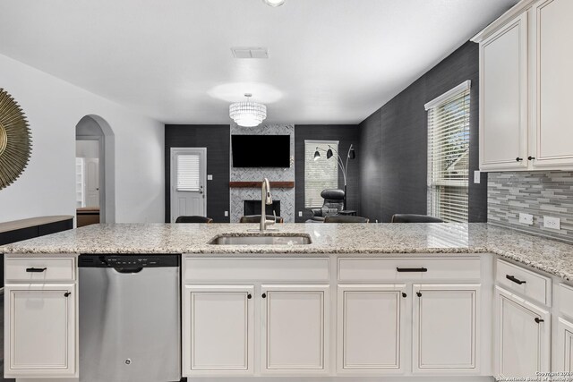 kitchen featuring white cabinetry, sink, light stone countertops, and stainless steel dishwasher